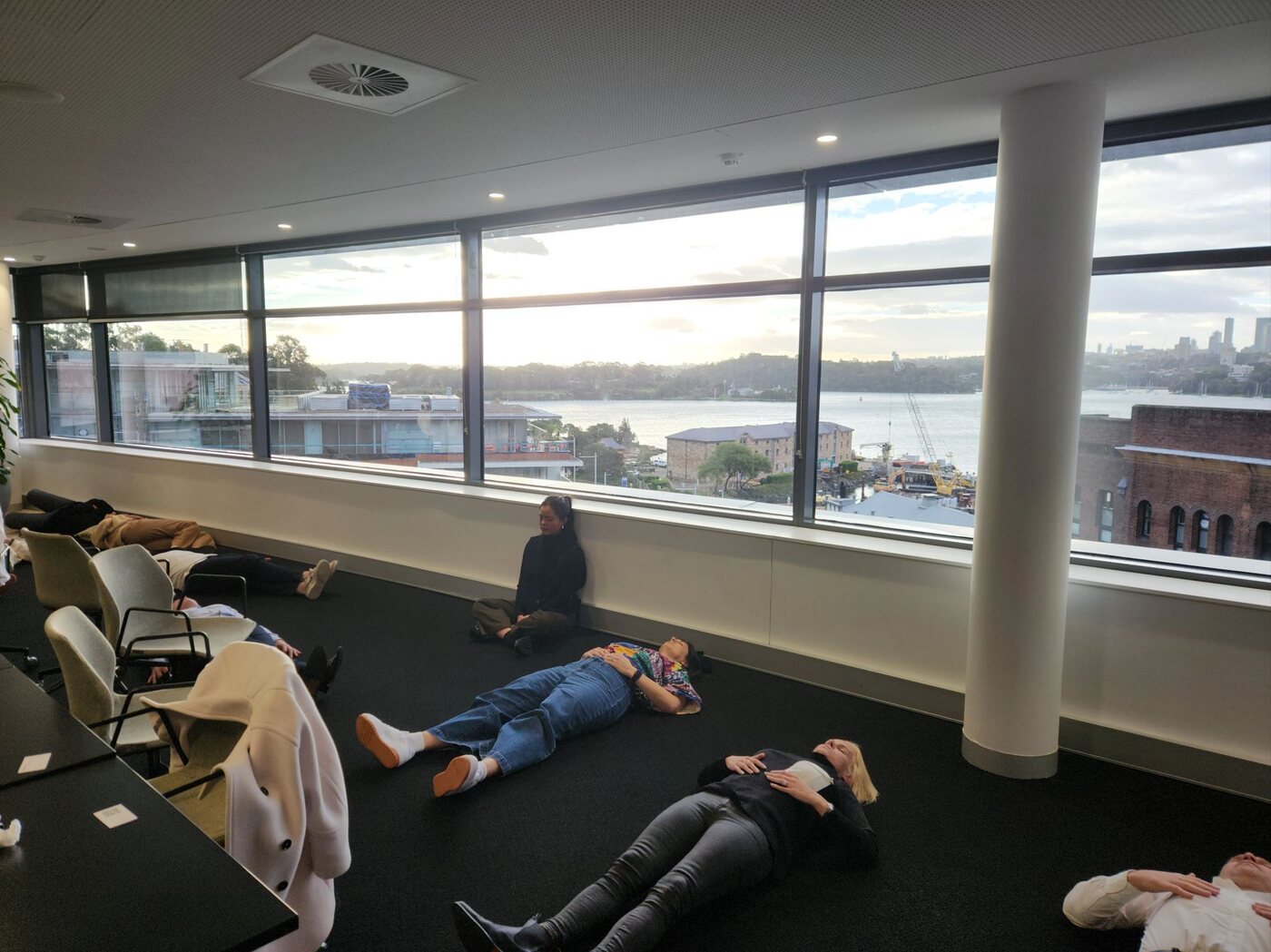 The iProspect team resting during a workplace breathwork session overlooking Sydney Harbour