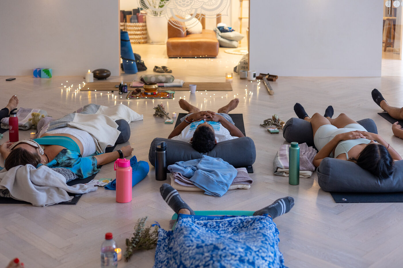 Participants resting on mats and bolsters by candlelight during the wind-down at the end of a group breathwork session.