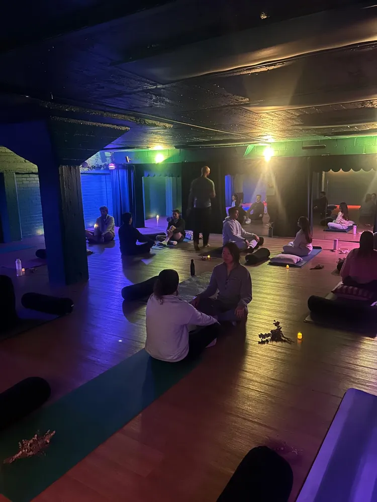 People sitting together on mats in a softly lit room during a Remindful evening session